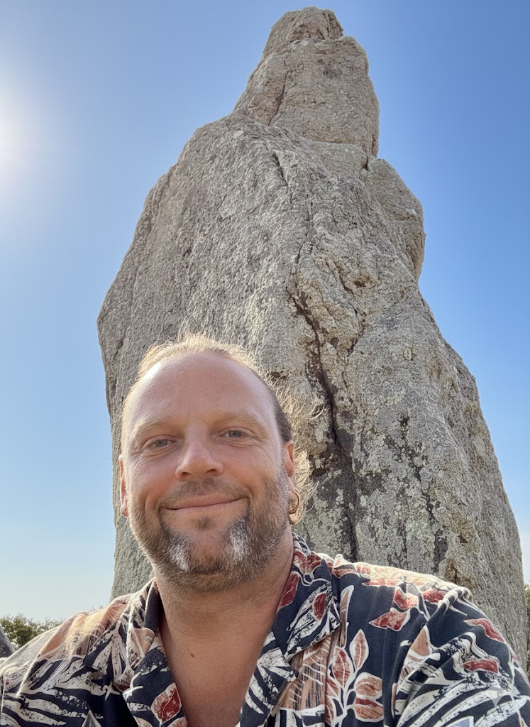 Julien devant un menhir en Bretagne, ciel bleu